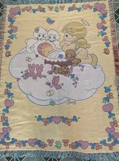 there is a blanket with two teddy bears on the cloud in the sky and flowers around it