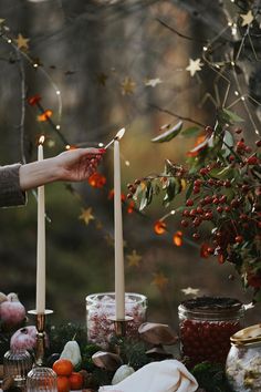 a person lighting candles on top of a table with food and decorations around the table