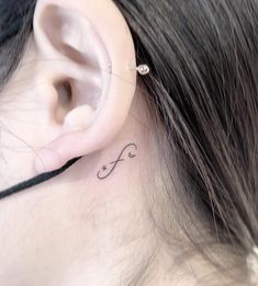 a woman's ear has a small tattoo on it