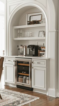 a kitchen with white cabinets and an open wine rack on the wall next to a dining room table