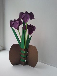 an origami vase with purple flowers in it