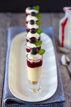 three desserts are arranged on a white plate with blueberries and mint garnish