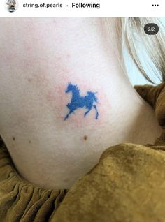 a blue horse tattoo on the back of a woman's neck is shown in this photo