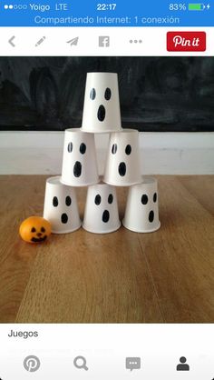 a stack of white cups sitting on top of a wooden table next to an orange