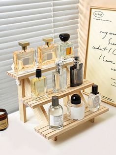 an assortment of perfumes on display in front of a sign and window with blinds