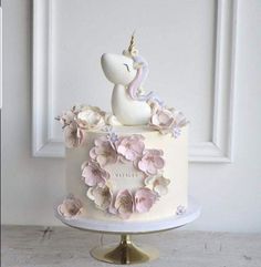 a white cake with pink flowers and a unicorn on top