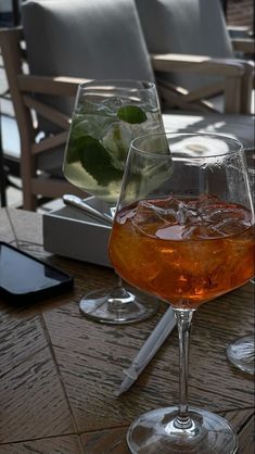 two glasses filled with liquid sitting on top of a wooden table