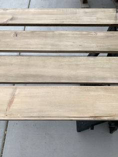 two wooden benches sitting next to each other on a cement floored area with tile