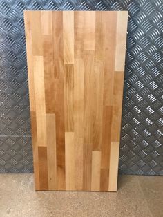 a large wooden cutting board sitting on top of a counter next to a metal wall