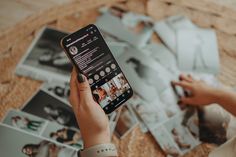 a person holding up a cell phone in front of some pictures on the floor with their hands