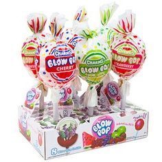 three lollipops are on display in a box with candy wrappers around them