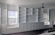 an empty room with built - in bookshelves and window shades on the windowsill