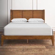 a bed with white pillows and wooden headboard in a room that has hardwood flooring