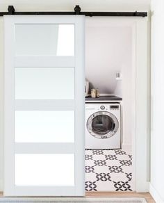 an open door leading to a washer and dryer in a room with white walls