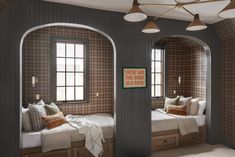 two twin beds in the corner of a room with arched windows and plaid wallpaper