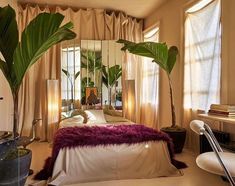 a bedroom with a bed, mirror and plants in it