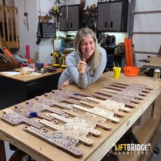 a woman sitting at a workbench making wooden letters