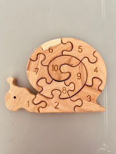 a wooden clock that is shaped like a snail and has numbers on the front side