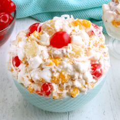 a bowl filled with fruit salad next to another bowl full of cherries and whipped cream