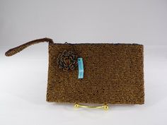 Very Sharp Beaded Clutch Purse of Shimmering Gold Tone Glass, With Wristlet, and Beaded Flower Accent.  NEW With Tag. Crafted By About Color. Measures 7" x 4". This Beautiful Gold Beaded Clutch Ships Free.  (1134) We  examine each listing and pass on to you our honest opinion of the item and it's condition.  As always your satisfaction   is of primary importance and should you be dissatisfied for any reason, please contact us immediately so that we can resolve the issue to ensure your satisfacti Gold Rectangular Wristlet For Gifts, Elegant Brown Wristlet For Evening, Elegant Brown Evening Wristlet, Elegant Adjustable Rectangular Wristlet, Elegant Gold Rectangular Wristlet, Gold Rectangular Wristlet With Wrist Strap, Elegant Gold Wristlet For Evening, Beaded Clutch Purse, Gold Purse