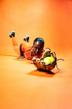 a woman laying on the ground with a ball and glove