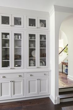 a white china cabinet with glass doors and drawers