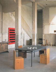 an empty room with tables and stools on the floor in front of a staircase