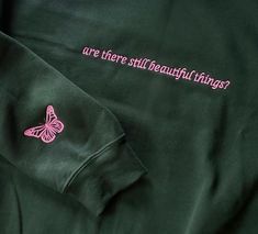 "Forest green pullover sweatshirt with \"are there still beautiful things?\" embroidered in pink thread on the front, a pink embroidered butterfly on the sleeve, and \"GOLD THREAD\" embroidered in pink on the back. Inspired by the song \"seven\" on Taylor Swift's album folklore. Small-large are Gildan brand. 50% cotton 50% polyester blend. Extra large is District fleece. 65% cotton 35% polyester blend." Saturn Necklace, Pink Thread, Green Pullover, Washing Hands, Last Minute Christmas Gifts, Best Friend Necklaces, Crescent Moon Pendant, Embroidered Butterfly, Butterfly Sleeve