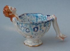 a porcelain figurine sitting in a blue and white bowl with bubbles on it