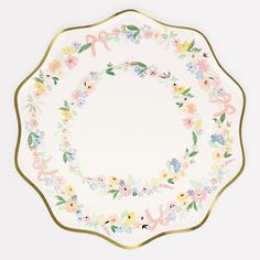 a white plate with flowers and gold trim around the edge, on a white background