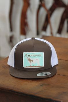 a brown and white trucker hat sitting on top of a wooden table next to some chairs