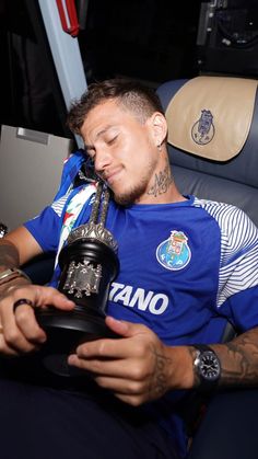 a man sitting in a chair with his head resting on a soccer ball and holding a trophy