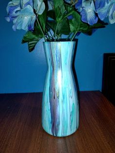 a blue vase filled with purple flowers on top of a wooden table next to a blue wall