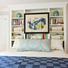 a bed with blue and white sheets in a bedroom next to bookshelves filled with books