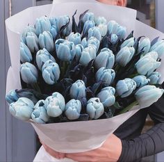 a man holding a bouquet of blue tulips