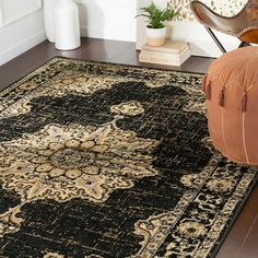 a black and beige rug with an ornate design on the floor next to a chair