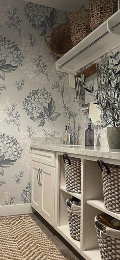 a bathroom with floral wallpaper and baskets on the counter top, along with two wicker baskets