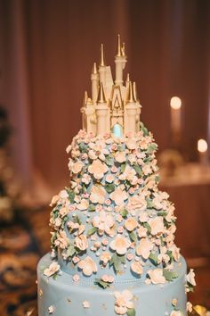 a blue cake with white flowers and a castle on top