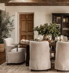 a dining room table and chairs with candles on them in front of a hutch