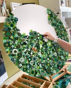 a person is working on an art project with green and white flowers in the center