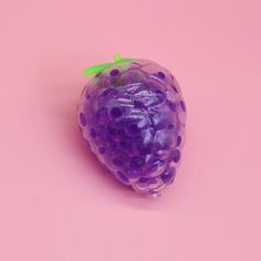 a close up of a purple fruit on a pink surface with polka dots and green leaves