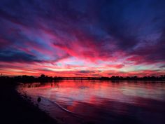 the sun is setting over water with clouds in the sky