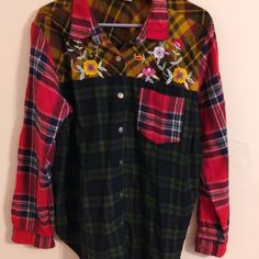 a plaid shirt with flowers is hanging on a hanger in front of a wall