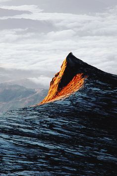 the top of a mountain is covered in clouds and sunlight as it rises into the distance