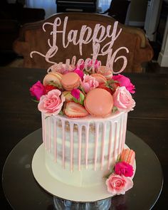 a white cake with pink frosting and flowers on top that says happy birthday next to it