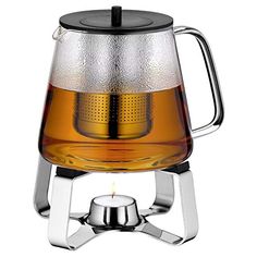 a glass tea pot with a metal holder