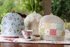 three tea bags and a cup on a table with flowers in the vase behind them