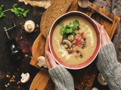 a person holding a bowl of mushroom soup