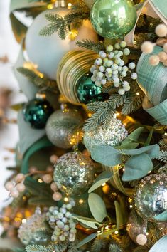 a christmas tree with green and gold ornaments on it's branches, including baubons