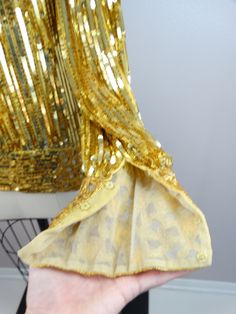 "This beautiful vintage piece is heavily embellished with gold sequins and beading. This piece is very well made and in perfect condition.. absolutely amazing!! Bust - 40\" Shoulders - 18\" Sleeves - 26\" Top Hem to Bottom Hem - 27\" Tag Size - Medium All of my items come from a smoke-free and pet-free home. If you have any questions, please don't hesitate to ask!" Gold Embellished Long Sleeve Sequin Dress, Glamorous Gold Long Sleeve Sequin Dress, Glamorous Gold Dress With Mirror Work, Gold Embellished Sequin Dress For Party Season, Gold Dress For Festive Costume Party, Glamorous Fitted Sequin Fabric For Celebration, Gold Long Sleeve Sequin Dress For Festive Occasions, Gold Sequin Dress With Contrast For Festive Occasions, Festive Gold Long Sleeve Sequin Dress